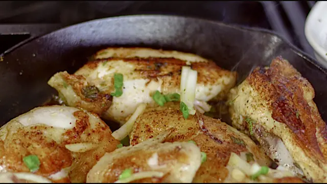 Fish cooking in a cast-iron skillet with herbs