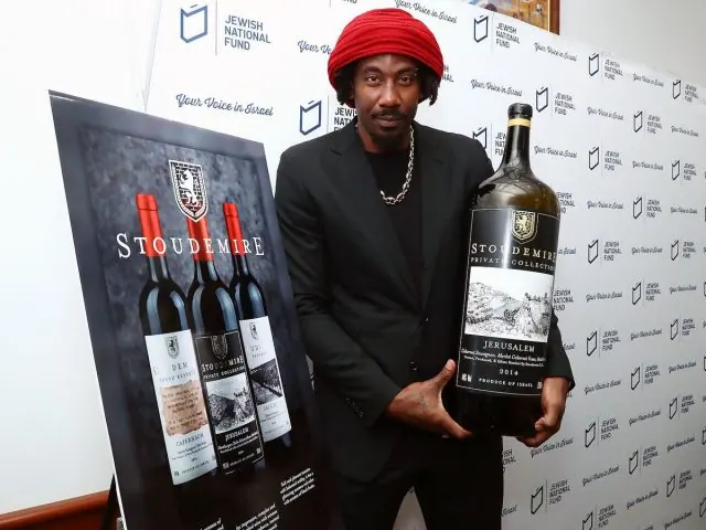 Amar'e Stoudemire holding a bottle of Stoudemire kosher wine beside a display of the label